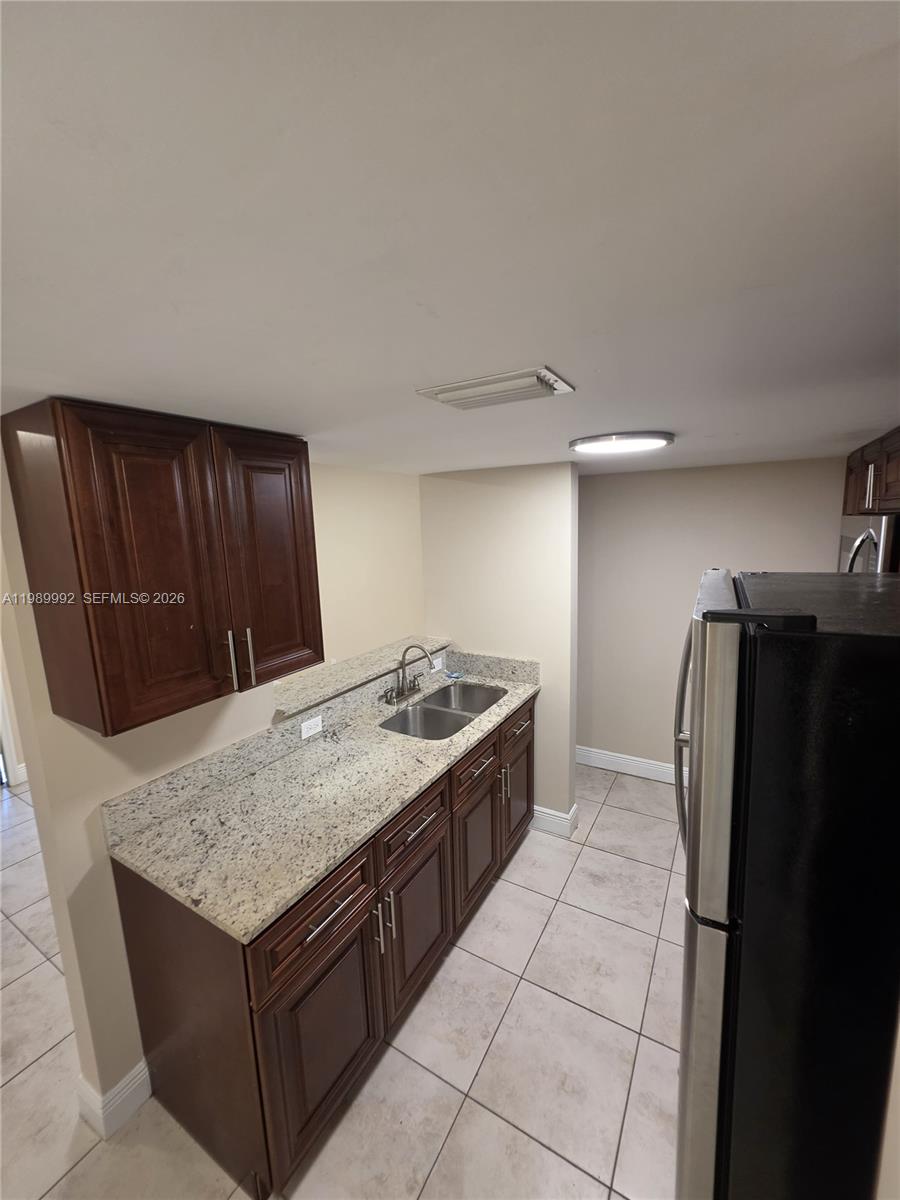 A kitchen features dark wood cabinets, granite countertops, a double sink, and tile flooring — 1990 NW 4th Ct # 7, Miami FL 33136, MIAMI, FL