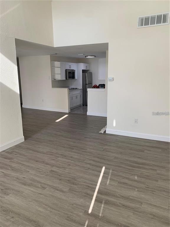 A view of a kitchen with white cabinets and stainless steel appliances from a living area — 17202 SANDALWOOD DRIVE UNIT 202, WILDWOOD, FL