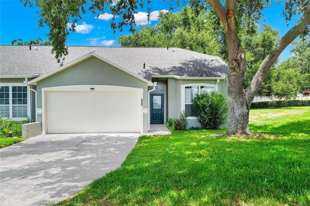 A one-story house with a garage, a dark blue front door, and a large tree — 648 HARBOR VILLA COURT UNIT 648, CLERMONT, FL