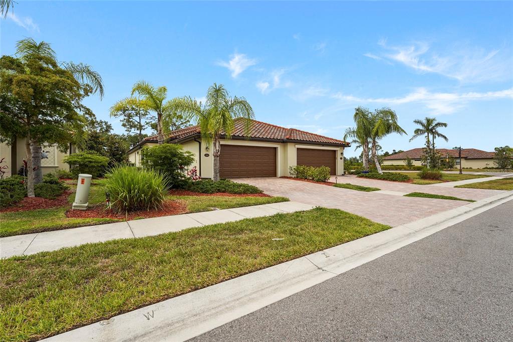 A single-story house with a two-car garage, tile roof, and palm trees in the front yard — 12055 AMICA LOOP, VENICE, FL