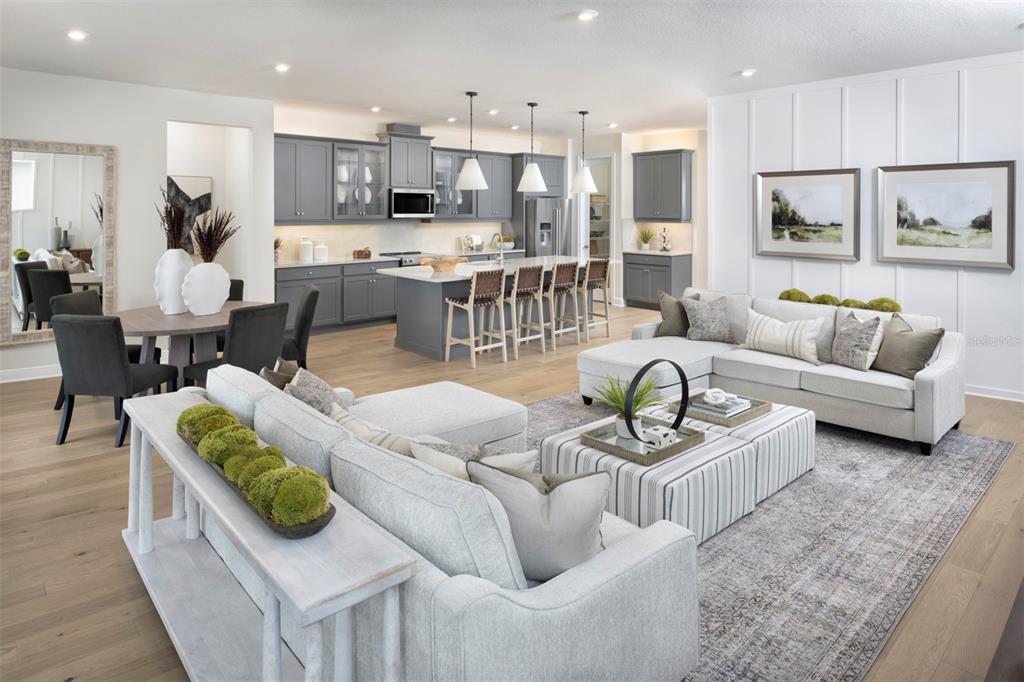 An open-concept living room and kitchen feature gray cabinetry, a large island, and light flooring — 18296 CHROMATA DRIVE, VENICE, FL
