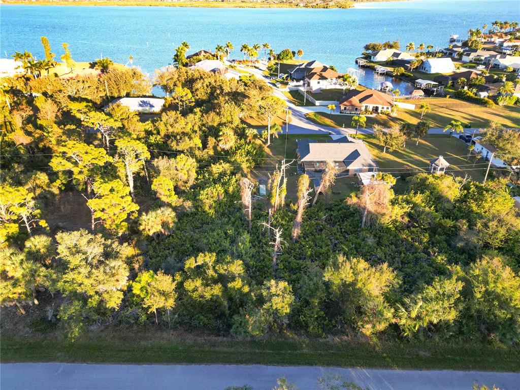 An aerial view shows a wooded lot situated near a residential street and coastal water — 3552 DWIGHT STREET, PORT CHARLOTTE, FL