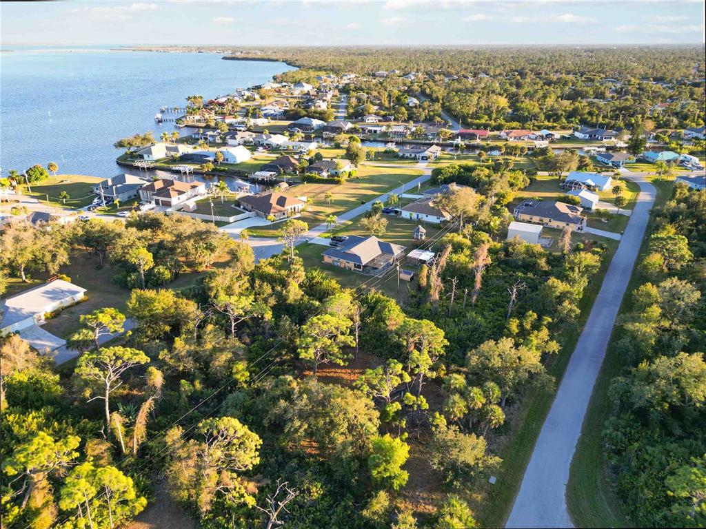 An aerial view shows a coastal neighborhood with houses, trees, and a road near water — 3552 DWIGHT STREET, PORT CHARLOTTE, FL