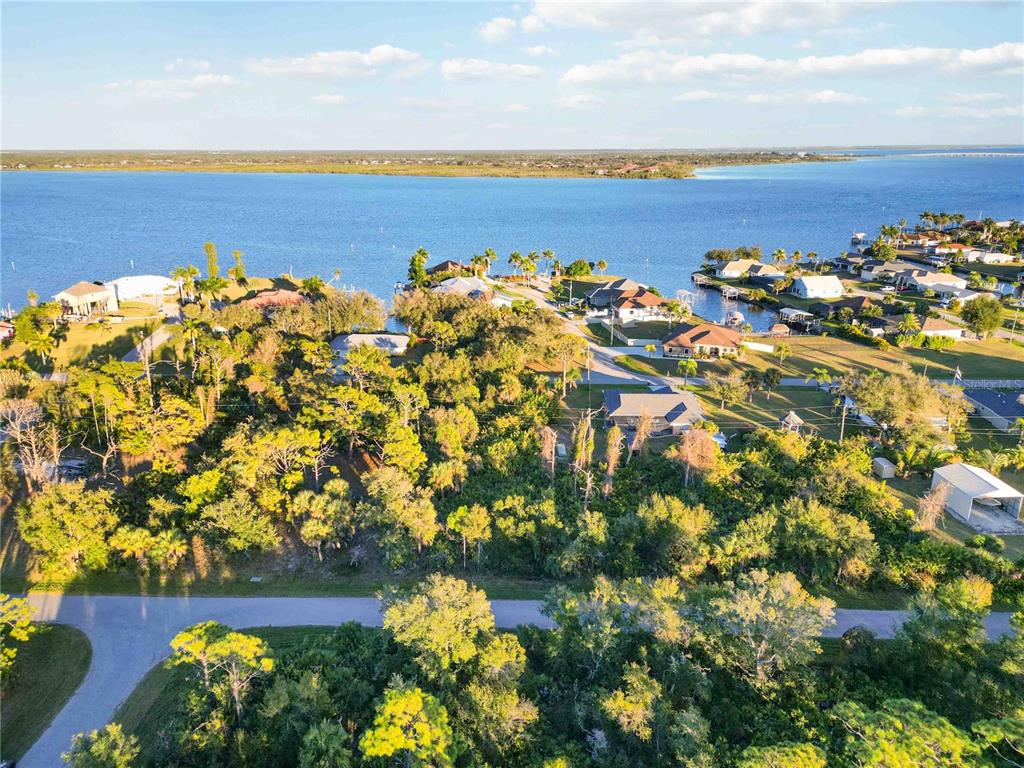 An aerial view shows a wooded residential lot near a large body of water — 3552 DWIGHT STREET, PORT CHARLOTTE, FL