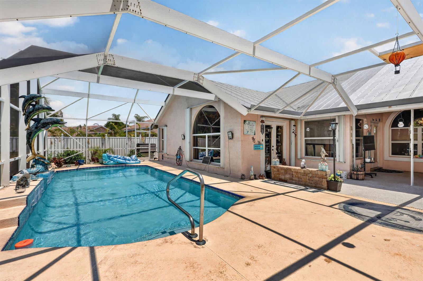 A screened-in swimming pool area features a tan concrete deck and a metal roof — 1921 NE Acapulco Drive, Jensen Beach FL 34957, JENSEN BEACH, FL