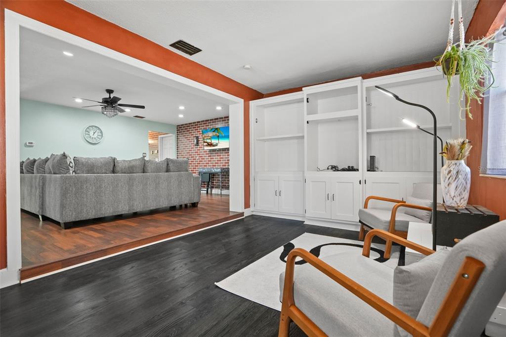 A living room with dark wood floors, built-in white shelving, and a sunken seating area — 1564 SANTA MONICA DRIVE, DUNEDIN, FL