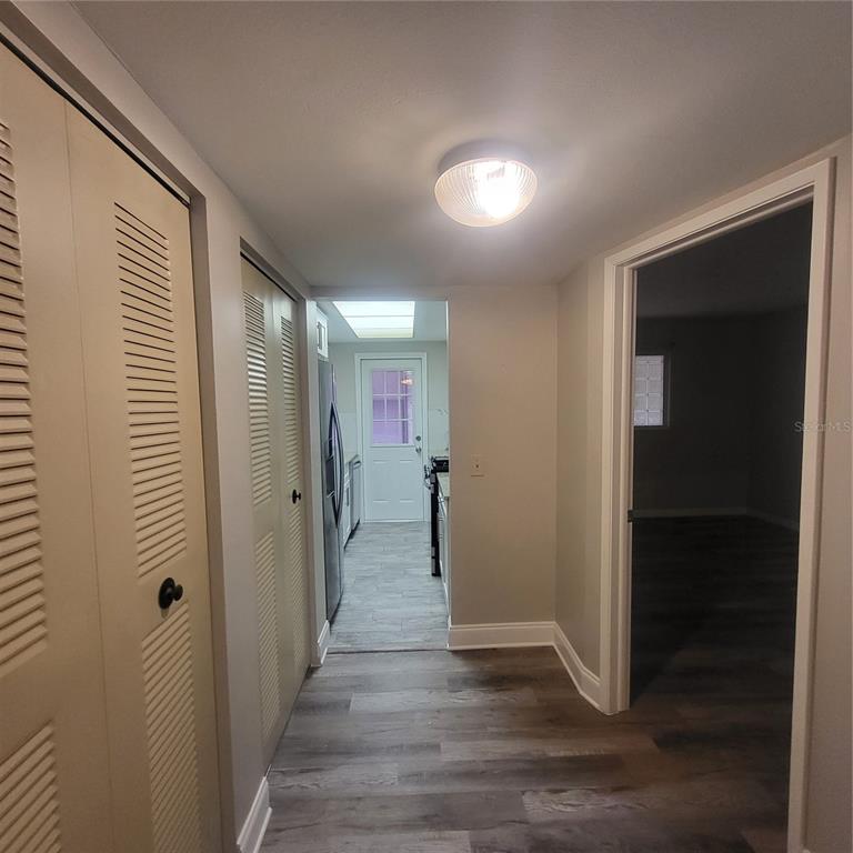 A hallway with louvered closet doors leads to a kitchen with a white exterior door — 911 WASHINGTON AVENUE UNIT 218, LARGO, FL
