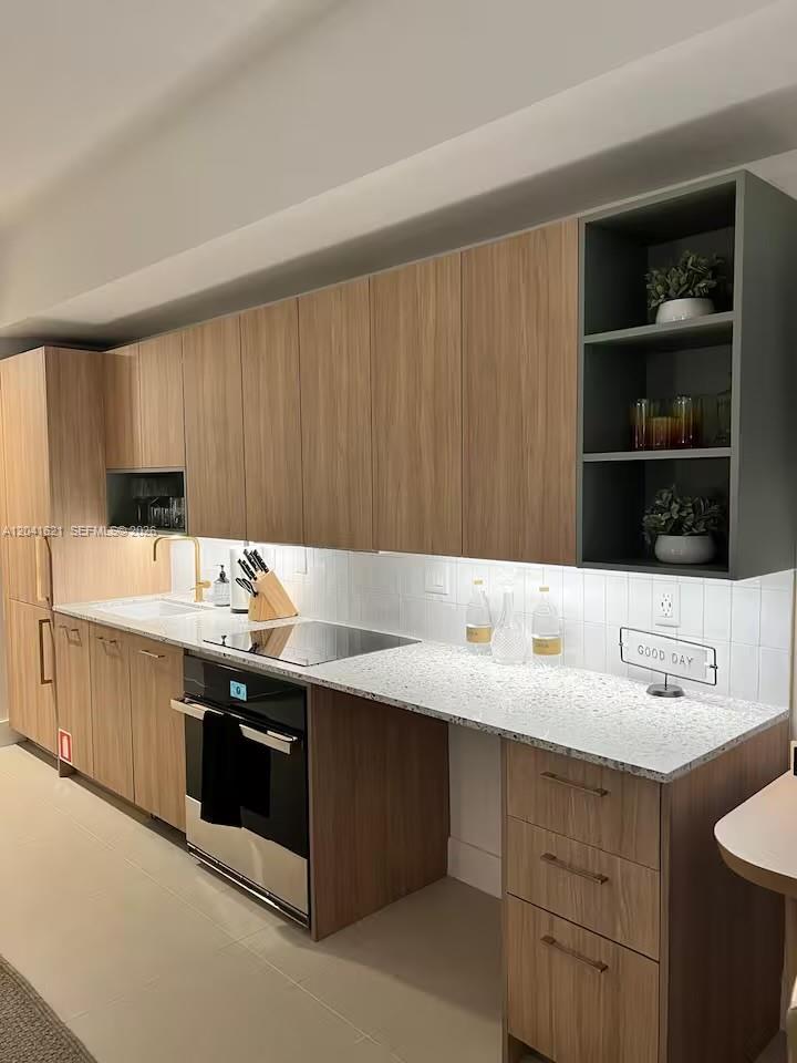 A modern kitchen features wood-grain cabinets, a white speckled countertop, and an open shelving unit — 159 NE 6th St # 2606, Miami FL 33132, MIAMI, FL