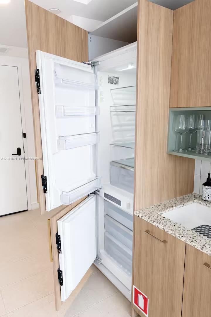 A kitchen features a built-in refrigerator with wood-paneled doors, light countertops, and a small sink — 159 NE 6th St # 2606, Miami FL 33132, MIAMI, FL