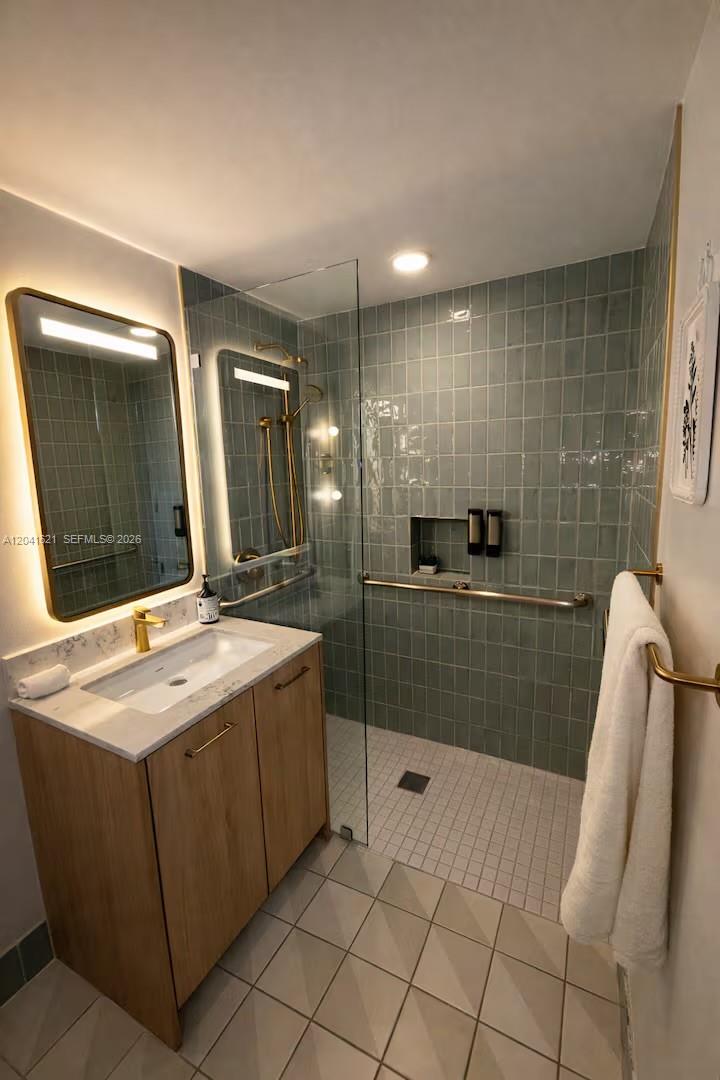 A modern bathroom features a wood vanity, a glass-enclosed shower, and sage green tile walls — 159 NE 6th St # 2606, Miami FL 33132, MIAMI, FL