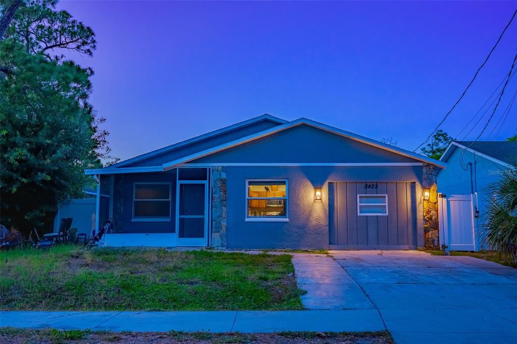 A blue single-story house with a screened front porch and a concrete driveway at dusk — 2423 23RD STREET, SARASOTA, FL