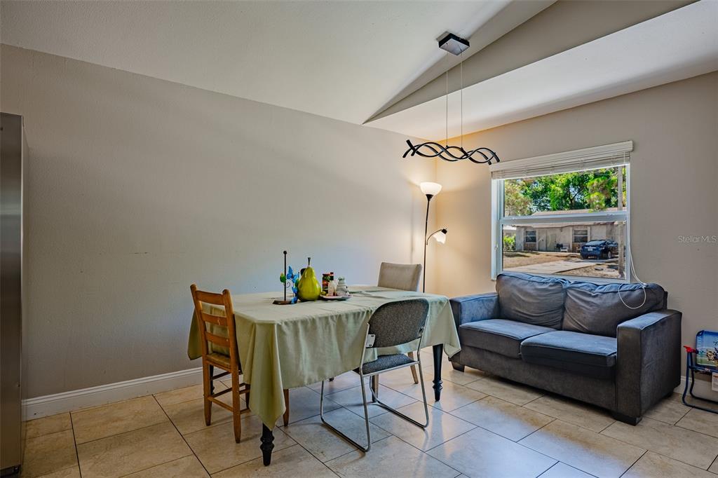 A dining area features a table with chairs, a grey sofa, and tile flooring — 2423 23RD STREET, SARASOTA, FL