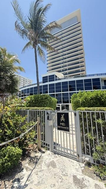 A tall modern residential building stands behind a gated entrance with a palm tree — 5875 Collins Ave # 708, Miami Beach FL 33140, MIAMI BEACH, FL