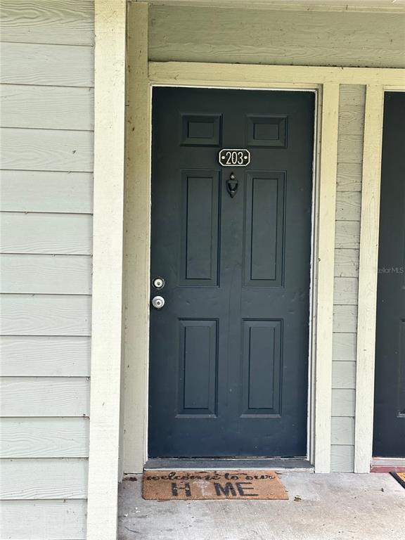 A dark-colored front door with a number 203 sign and a welcome mat — 6052 WESTGATE DRIVE UNIT 203, ORLANDO, FL
