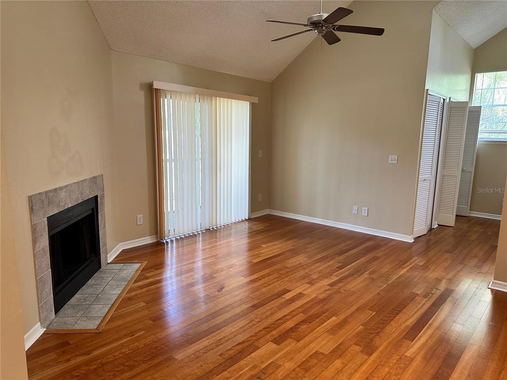 A living room with hardwood floors, a fireplace, vaulted ceilings, and sliding glass doors — 6052 WESTGATE DRIVE UNIT 203, ORLANDO, FL