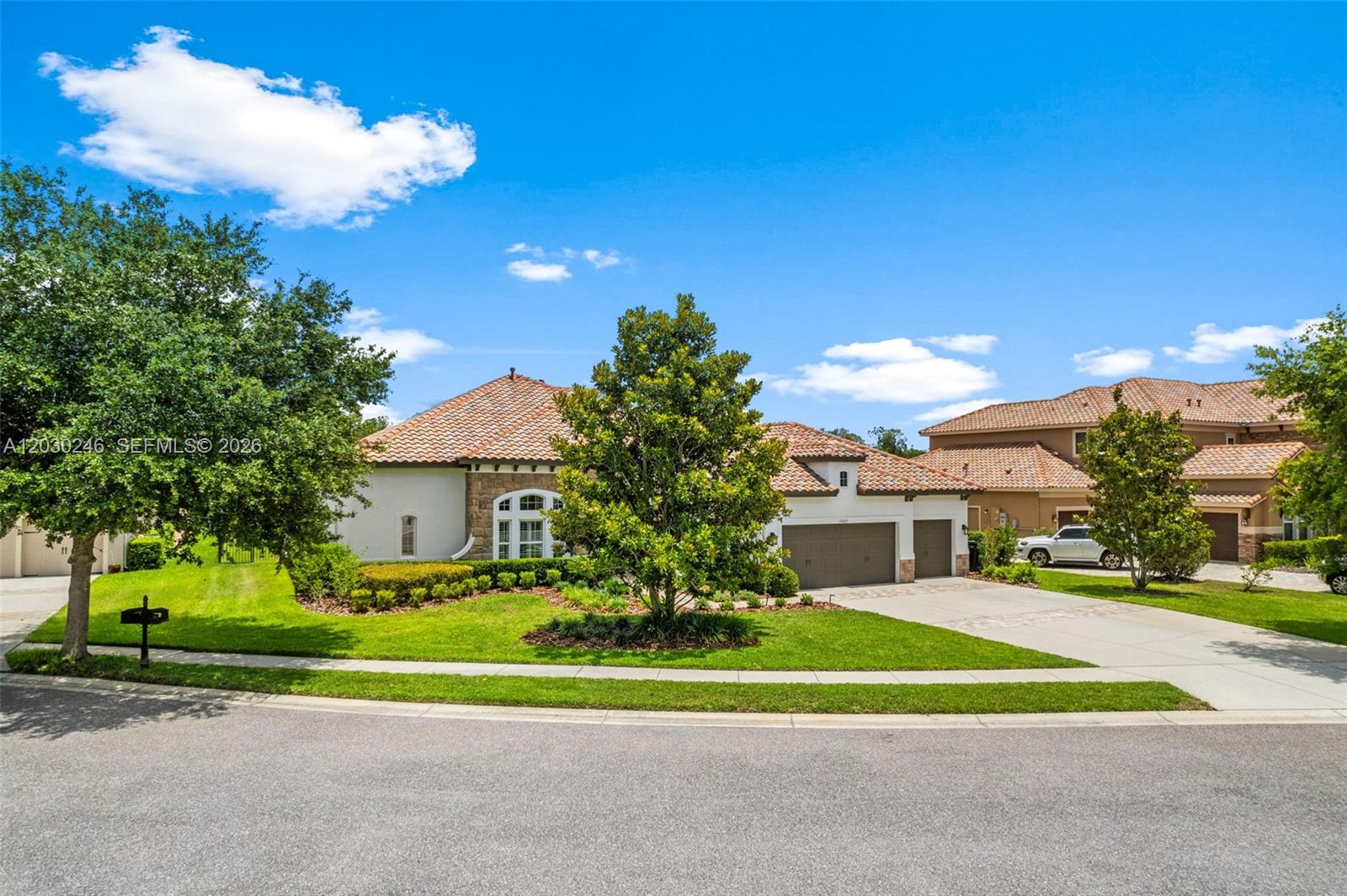 A single-story house with a tile roof, stone accents, and a three-car garage — 17425 Varona Pl, Lutz FL 33548, LUTZ, FL