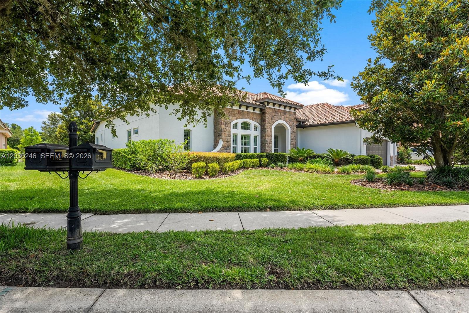A single-story house with a stone facade, tile roof, and a manicured front lawn — 17425 Varona Pl, Lutz FL 33548, LUTZ, FL