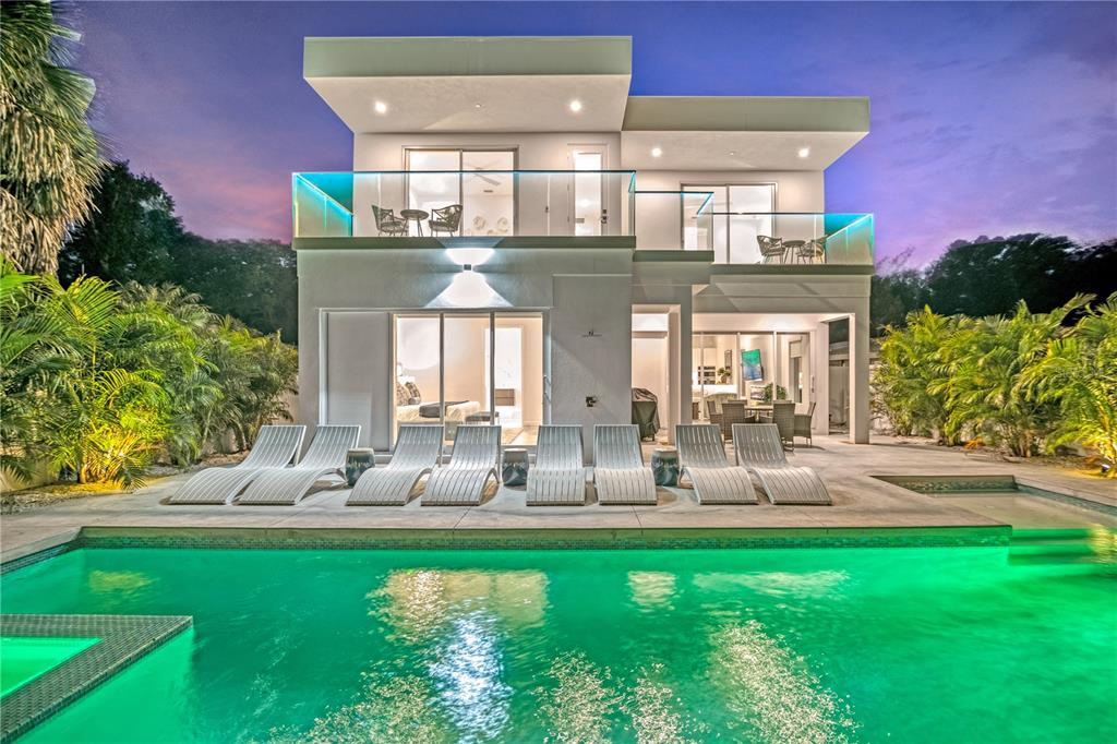 A modern two-story house with a swimming pool, lounge chairs, and balconies at dusk — 2327 HILLVIEW STREET, SARASOTA, FL
