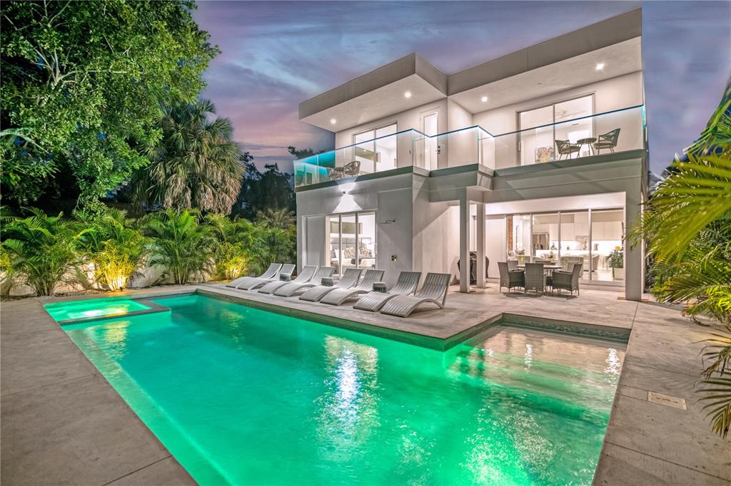 A modern two-story house with a lit swimming pool, lounge chairs, and a glass-railed balcony — 2327 HILLVIEW STREET, SARASOTA, FL