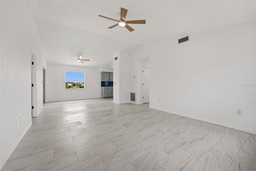 A bright, open-concept living area features white walls, light wood-look tile flooring, and ceiling fans — 192 ANNAPOLIS LANE, ROTONDA WEST, FL