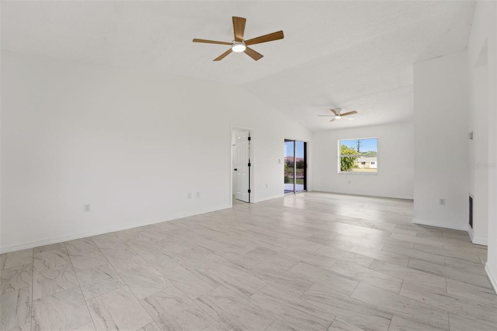 A spacious, empty living room with white walls, light tile flooring, and two ceiling fans — 192 ANNAPOLIS LANE, ROTONDA WEST, FL