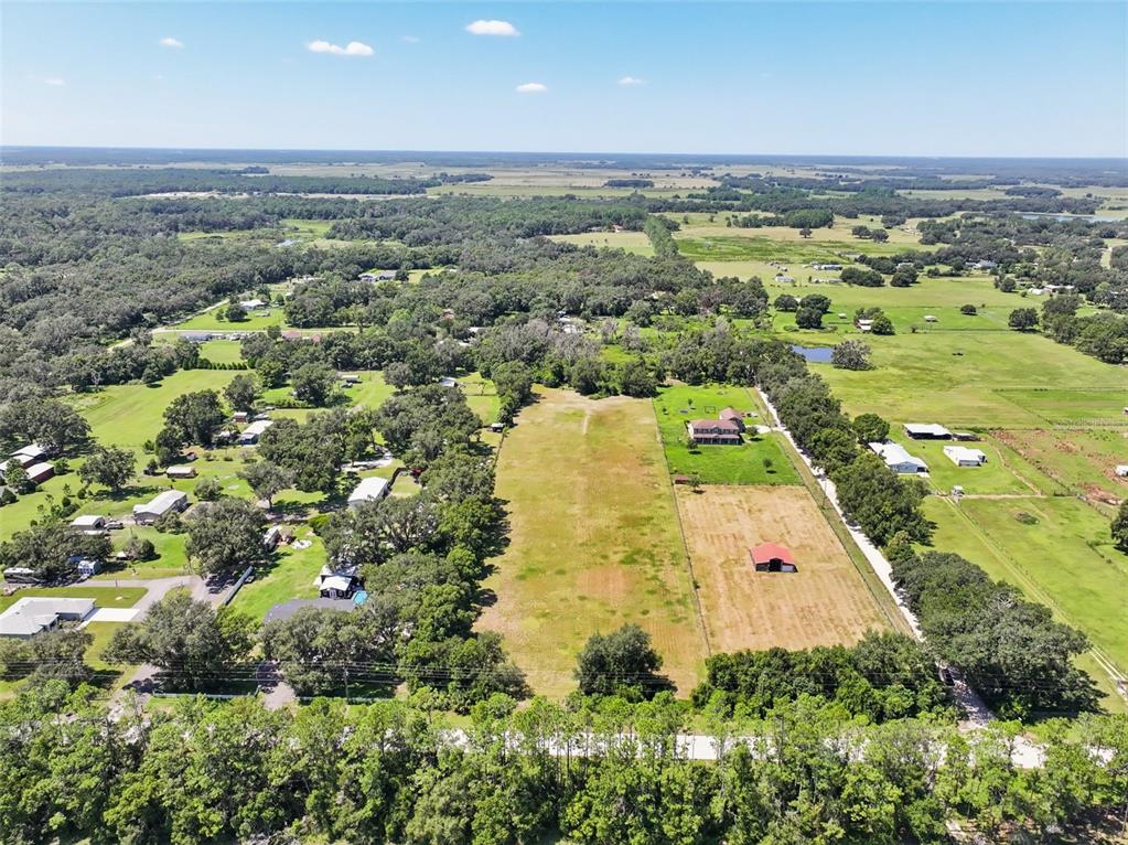 A wide, grassy field is bordered by a line of mature trees under a cloudy sky — BELLAMY BROTHERS BOULEVARD, DADE CITY, FL