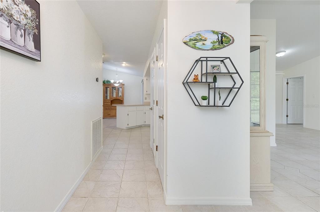 A hallway with tiled floors leads to a kitchen featuring white cabinets and a hutch — 23235 MCQUEENEY AVENUE, PUNTA GORDA, FL