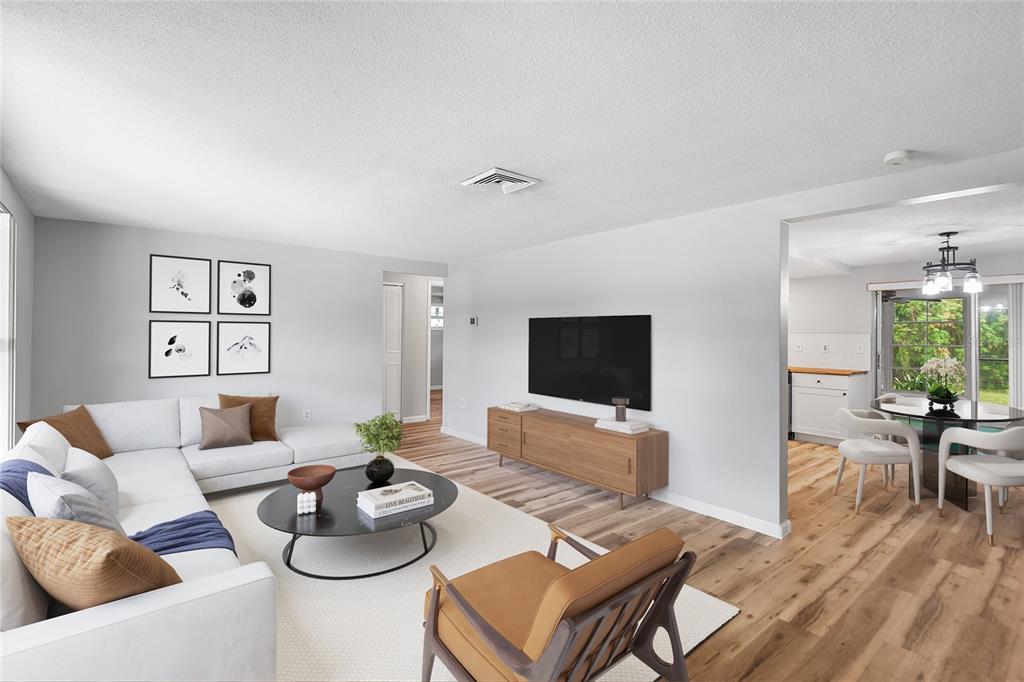 A living room features a white sectional sofa, a wooden media console, and wood flooring — 7913 RAINTREE DRIVE, NEW PORT RICHEY, FL