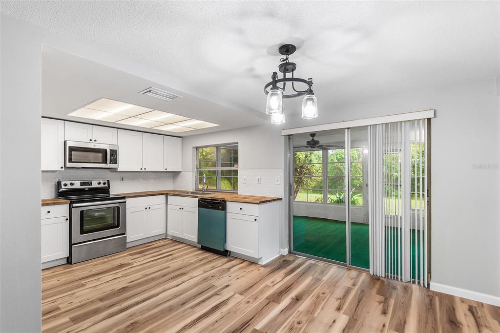 A kitchen with white cabinets, wood countertops, stainless steel appliances, and a sliding glass door — 7913 RAINTREE DRIVE, NEW PORT RICHEY, FL