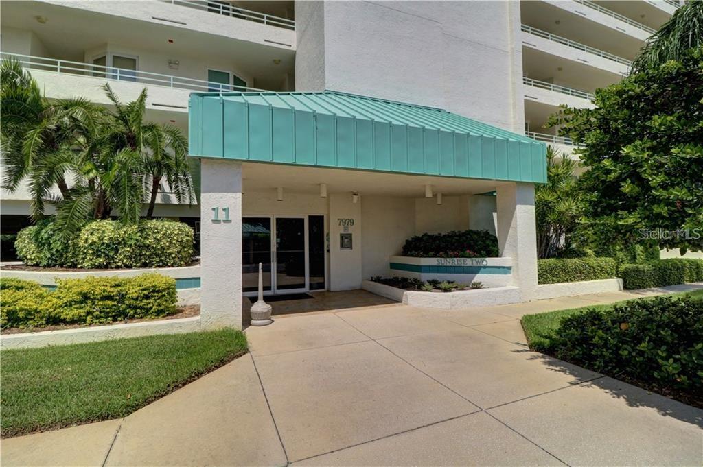The exterior entrance of a multi-story residential building features a teal metal awning — 7979 SAILBOAT KEY BOULEVARD S UNIT 306, SOUTH PASADENA, FL