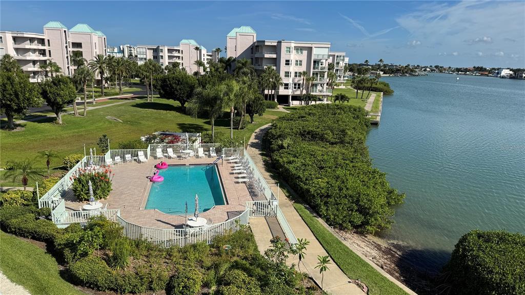 An elevated view of a swimming pool area beside a building and a waterway — 7979 SAILBOAT KEY BOULEVARD S UNIT 306, SOUTH PASADENA, FL