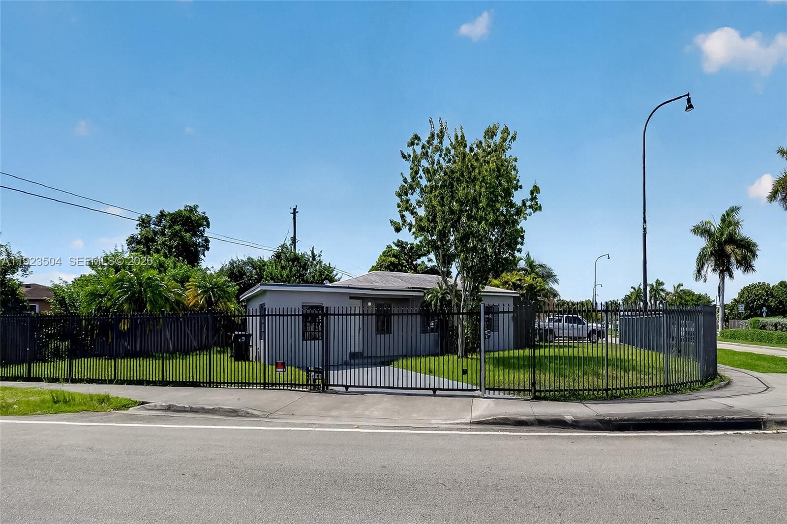 A single-story gray house is enclosed by a black metal fence on a corner lot — 14801 Lincoln Blvd, Miami FL 33176, MIAMI, FL