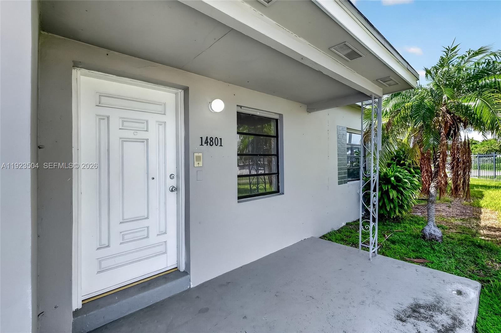 A white front door with a decorative frame sits on a gray concrete porch — 14801 Lincoln Blvd, Miami FL 33176, MIAMI, FL