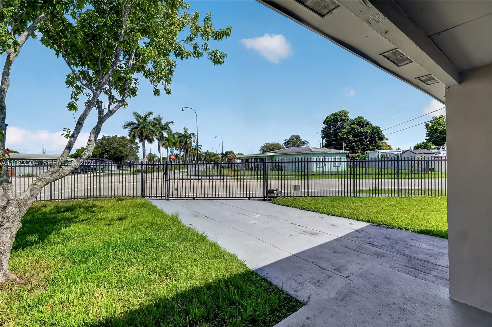 A paved driveway leads to a metal gate in front of a residential street — 14801 Lincoln Blvd, Miami FL 33176, MIAMI, FL