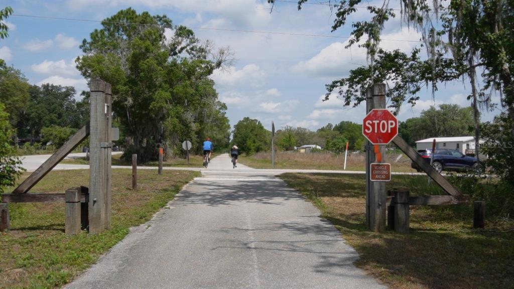 A paved trail passes through a wooden gate with a stop sign at a road crossing — 0, POLK CITY, FL