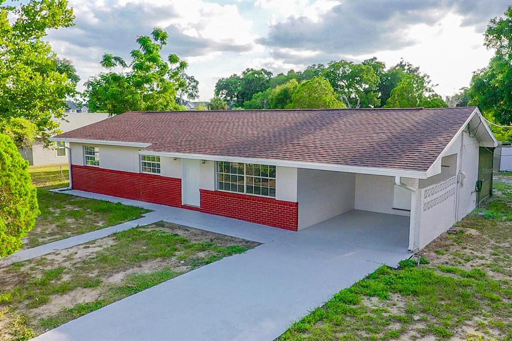 A single-story house with a red brick base, white stucco walls, and an attached carport — 2104 SW 38TH AVENUE, OCALA, FL