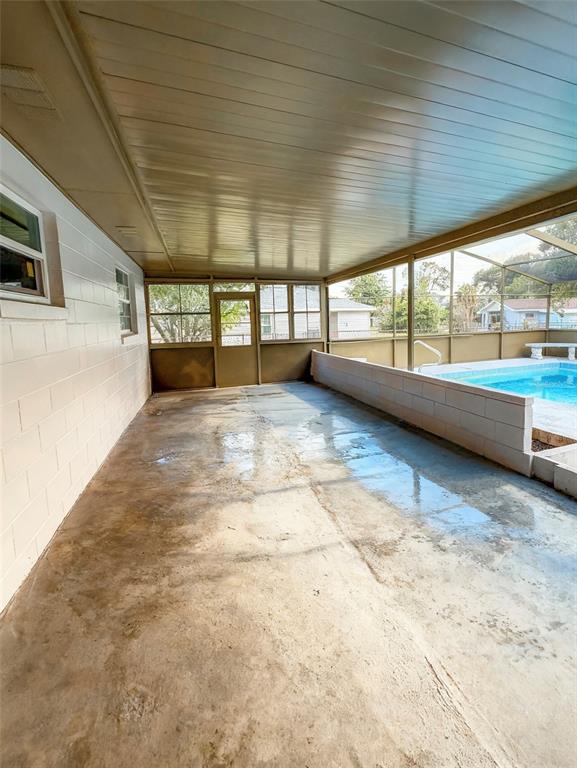 A covered concrete patio features a screened enclosure overlooking an outdoor swimming pool — 2104 SW 38TH AVENUE, OCALA, FL