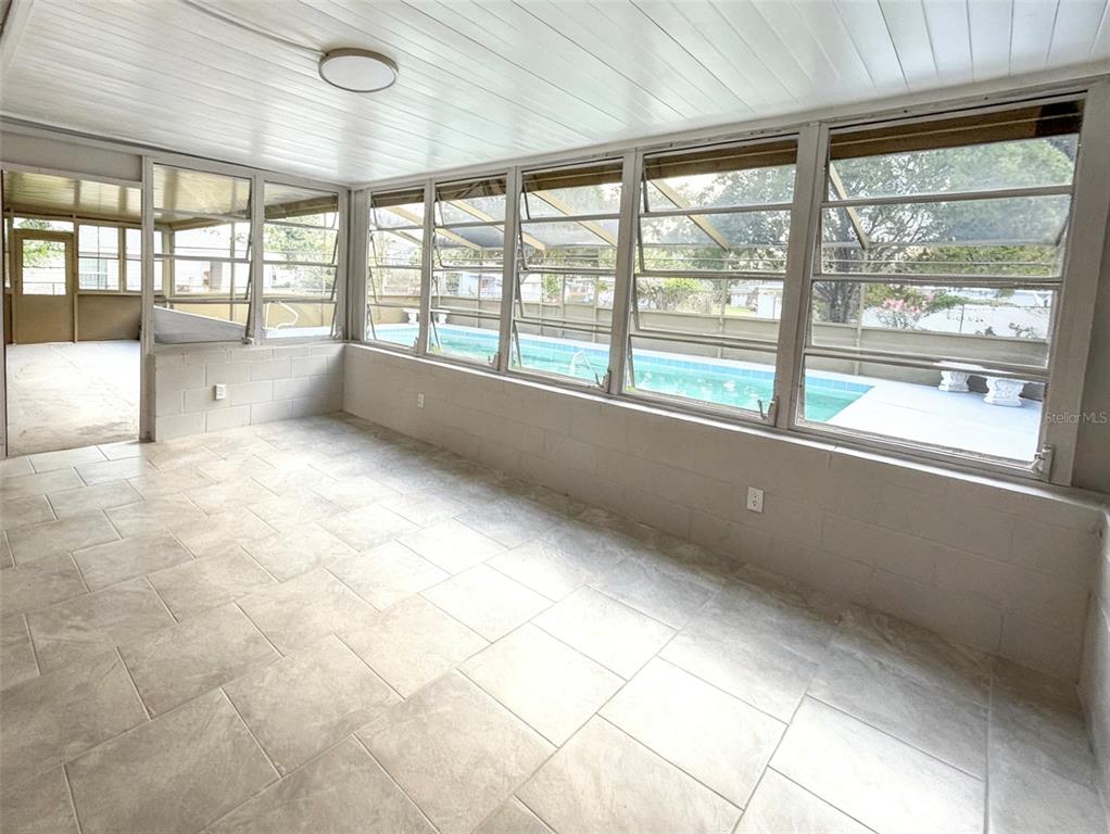 A sunroom with tiled floors and large windows overlooking a swimming pool — 2104 SW 38TH AVENUE, OCALA, FL
