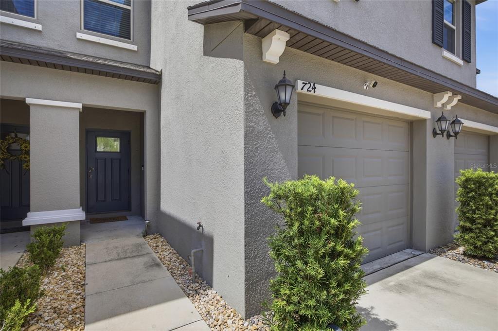 The exterior of a gray stucco townhouse features a garage, a front entrance, and landscaping — 724 ROYAL EMPRESS DRIVE, RUSKIN, FL