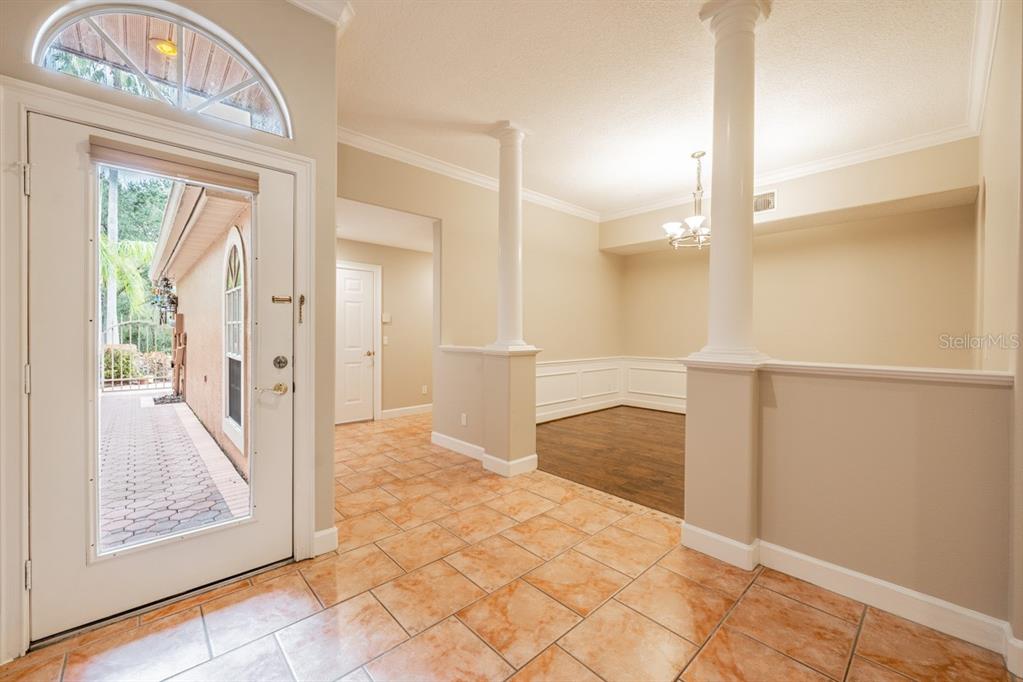 An entryway with tile flooring leads to a dining area featuring columns and wood floors — 1626 LAGO VISTA BOULEVARD, PALM HARBOR, FL