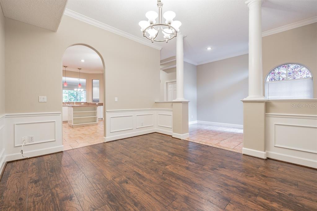 A dining room with wood flooring, white wainscoting, a chandelier, and arched entryways — 1626 LAGO VISTA BOULEVARD, PALM HARBOR, FL