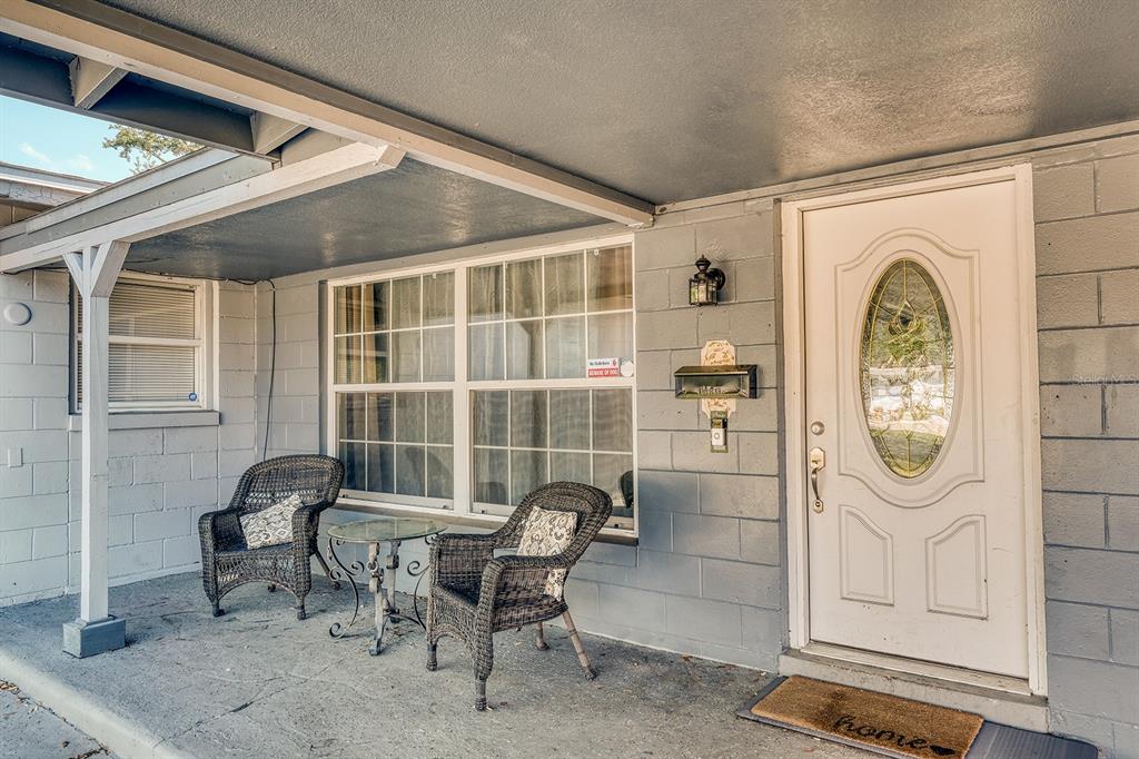 A covered front porch features two wicker chairs, a small table, and a white door — 5919 LUZON DRIVE, ORLANDO, FL