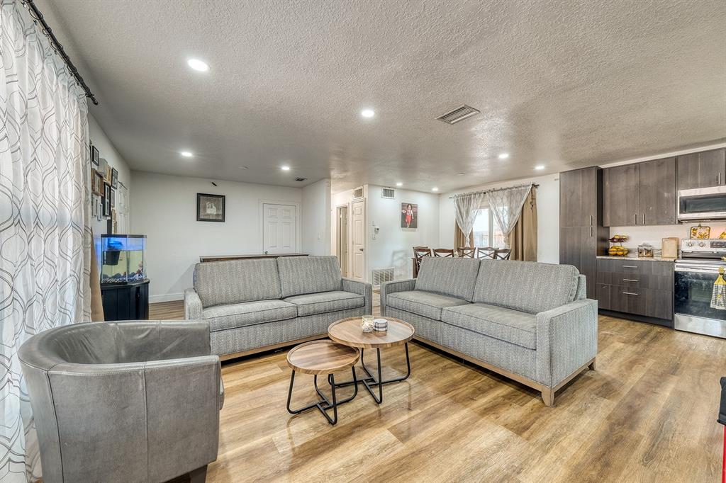 A living room with gray sofas, a leather armchair, nesting coffee tables, and an open kitchen — 5919 LUZON DRIVE, ORLANDO, FL