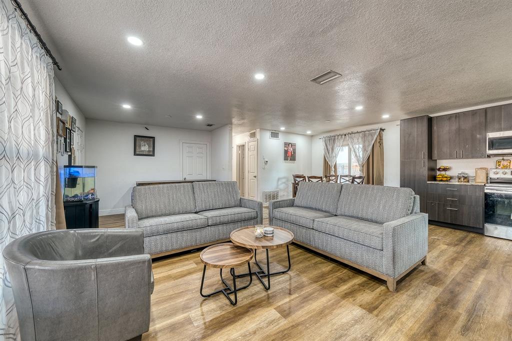 A living room with two gray sofas, a leather chair, and wood-look flooring — 5919 LUZON DRIVE, ORLANDO, FL