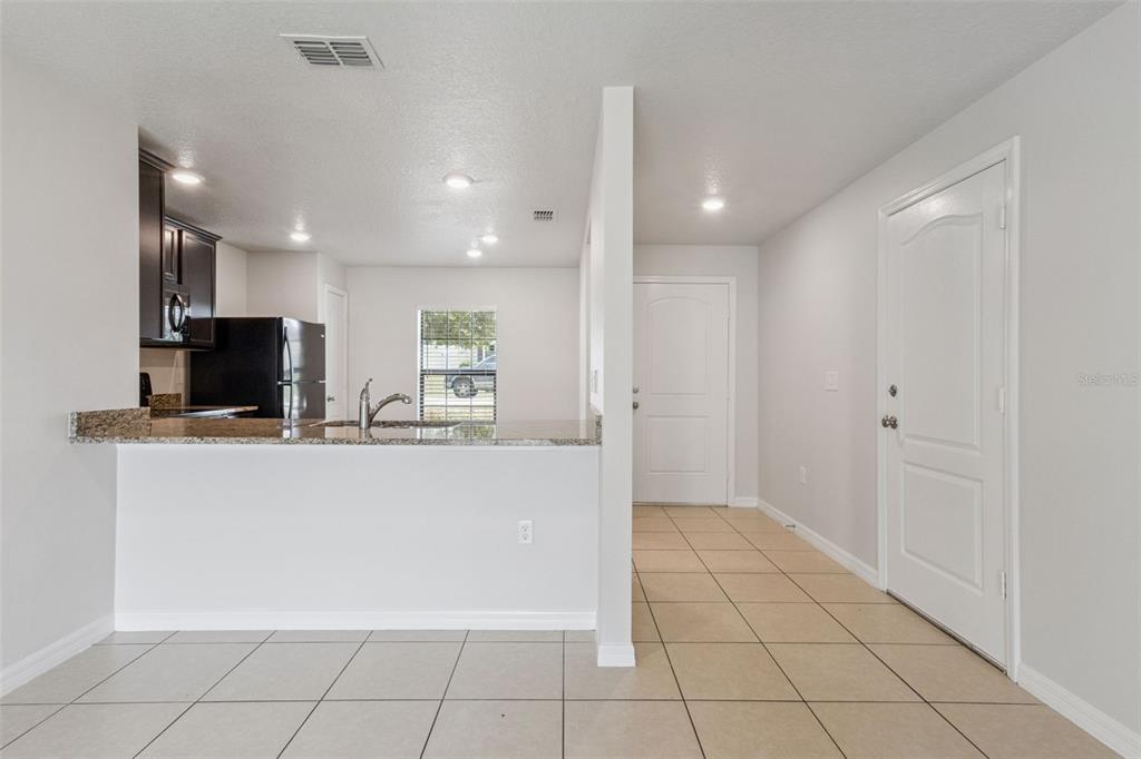 A kitchen with dark cabinets and a breakfast bar opens to a tiled entryway — 1613 ORNE STREET, MASCOTTE, FL