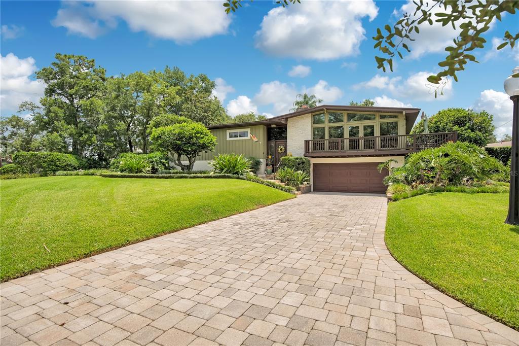 A wooden deck with patio furniture overlooks a lake surrounded by trees and greenery — 800 GATLIN AVENUE, ORLANDO, FL