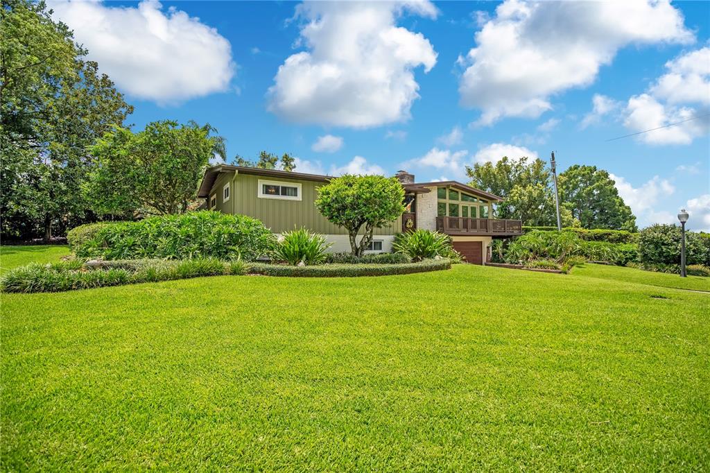 A split-level house exterior features a stone facade, olive green siding, and a paved driveway — 800 GATLIN AVENUE, ORLANDO, FL