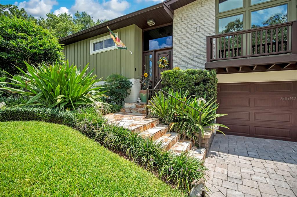 A split-level house with a paved driveway, green siding, and a second-story balcony — 800 GATLIN AVENUE, ORLANDO, FL