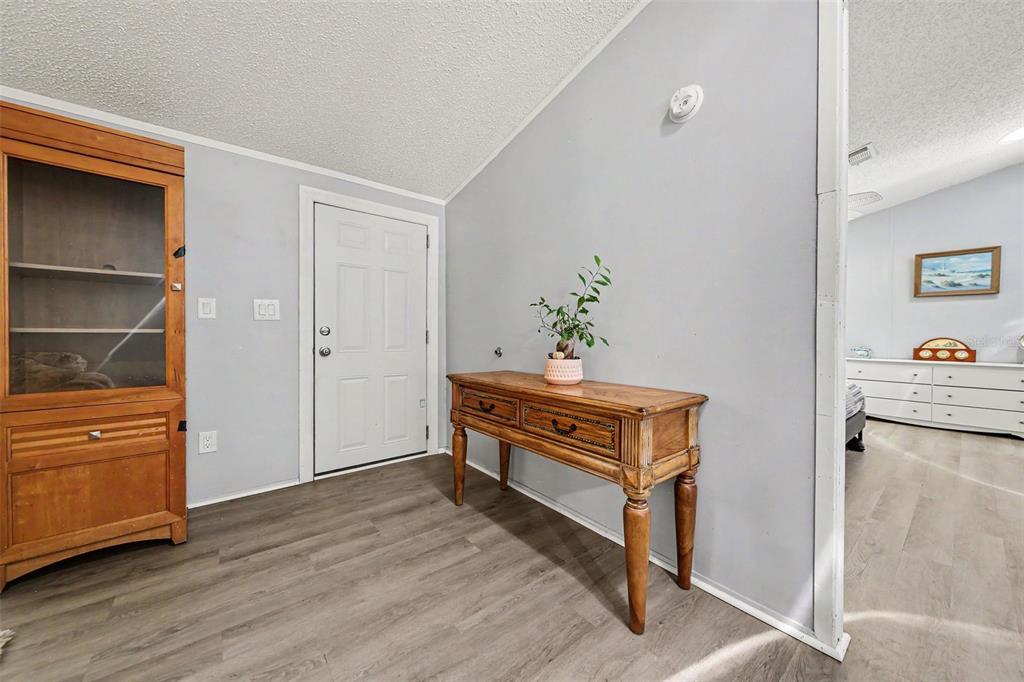 An entryway features wood-look flooring, a wooden console table, and a white front door — 2375 GROVE STREET, BUNNELL, FL