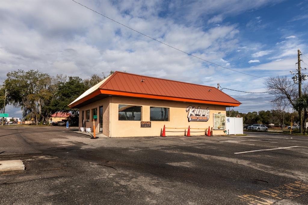 A single-story commercial building with a brown metal roof and a drive-thru window — 299 E BROAD STREET, GROVELAND, FL